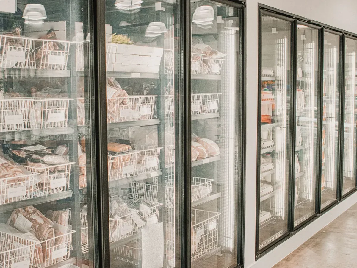 Packs of frozen meat behind the glass doors of a freezer case